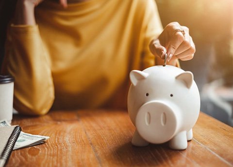 a person putting coins in a piggy bank 