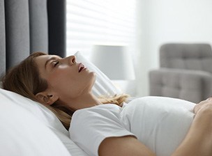 a woman with sleep apnea snoring in bed