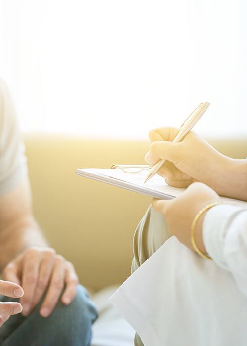 Doctor taking notes during conversation with patient