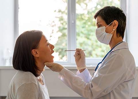 Doctor performing throat and mouth examination