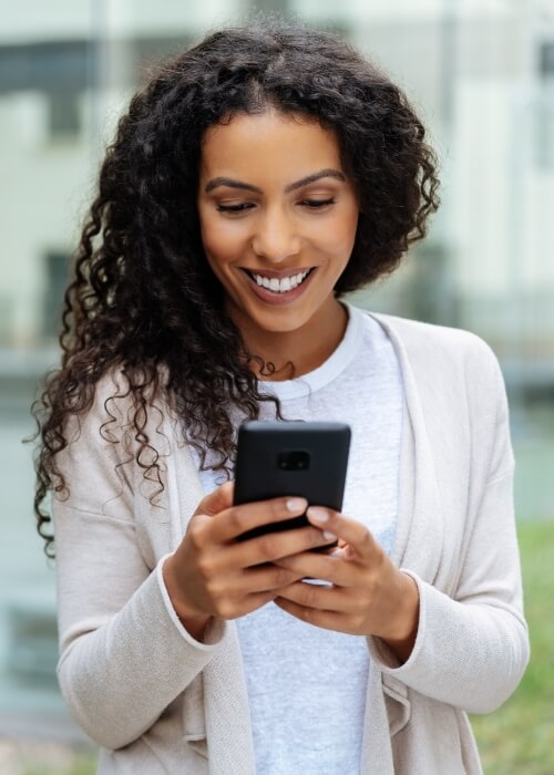 Smiling woman using her phone to contact dental sleep office in Cumming