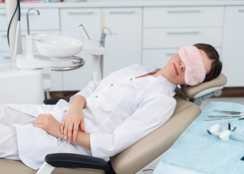 Woman relaxing in dental treatment chair with eye mask on