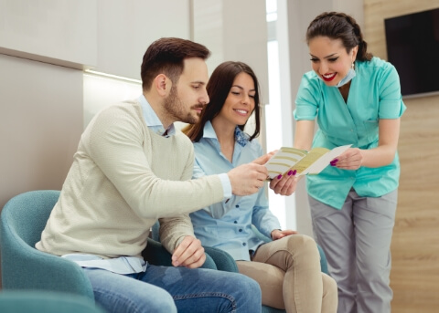 Dental team member showing a pamphlet to two patients