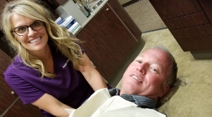 Doctor Bragg smiling next to man in dental treatment chair