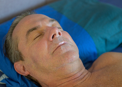 Man sleeping on his back with his mouth taped shut