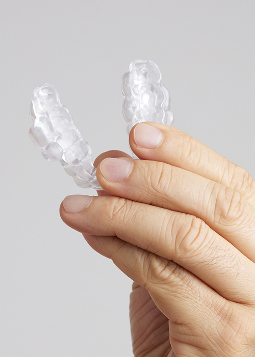 Hand holding a clear oral appliance for sleep apnea in Cumming