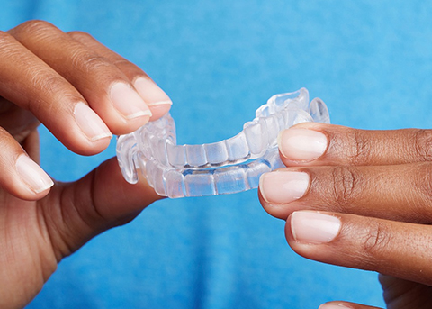 Close up of hands holding a clear oral appliance