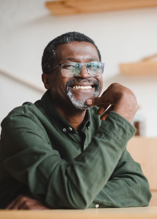 Smiling senior man with glasses sitting at table