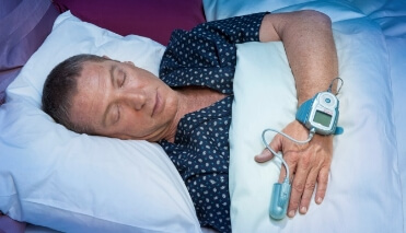 Man sleeping while wearing pulse oximeter on his hand