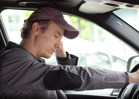 Man dozing off while sitting in drivers seat of car