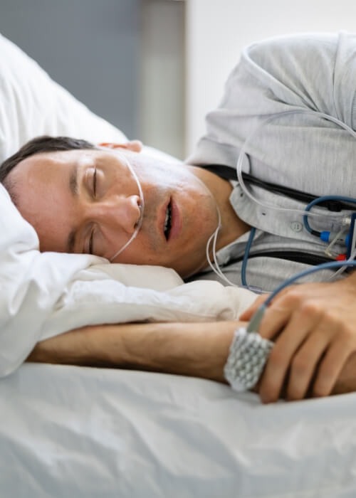 Sleeping man wearing pulse oximeter on his hand for sleep testing in Cumming