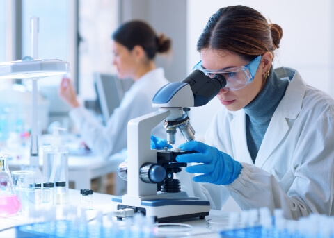 Woman in white lab coat looking at something under a microscope