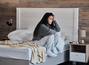 Depressed woman sitting on her bed