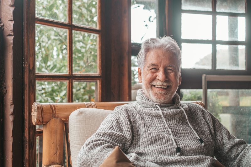 an older man smiling while relaxing at home